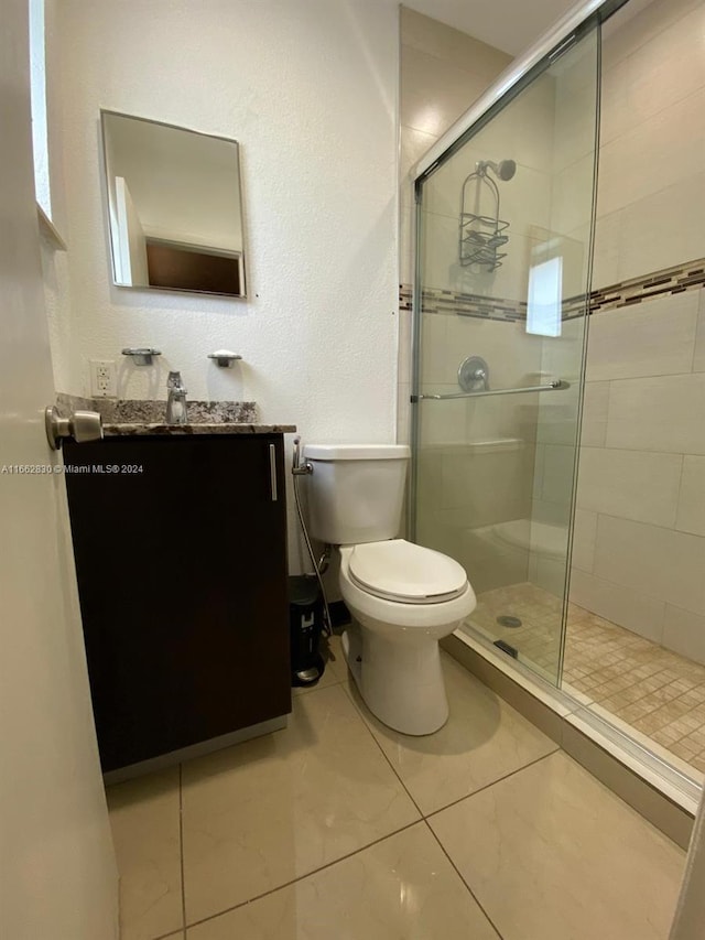 bathroom with an enclosed shower, vanity, toilet, and tile patterned floors