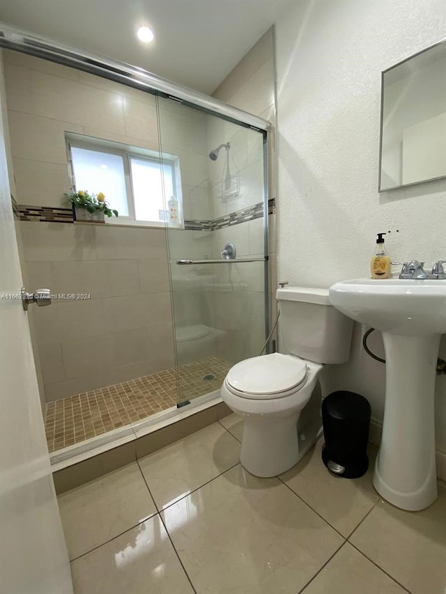 bathroom featuring tile patterned floors, sink, a shower with shower door, and toilet