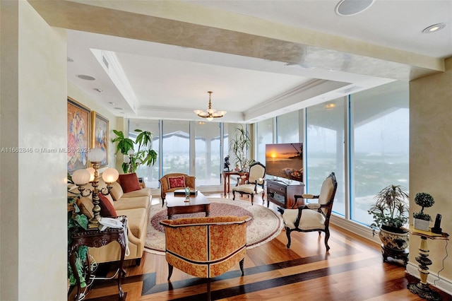 living room with a raised ceiling, plenty of natural light, hardwood / wood-style floors, and an inviting chandelier