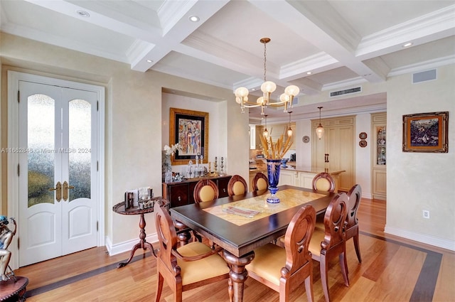 dining space featuring coffered ceiling, an inviting chandelier, and light hardwood / wood-style floors