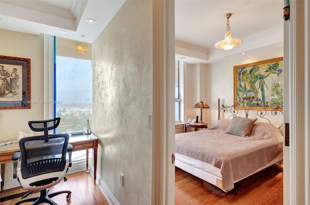 bedroom with hardwood / wood-style flooring, crown molding, and a raised ceiling