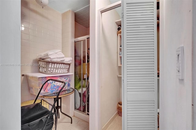 bathroom with tile patterned flooring, walk in shower, and tile walls