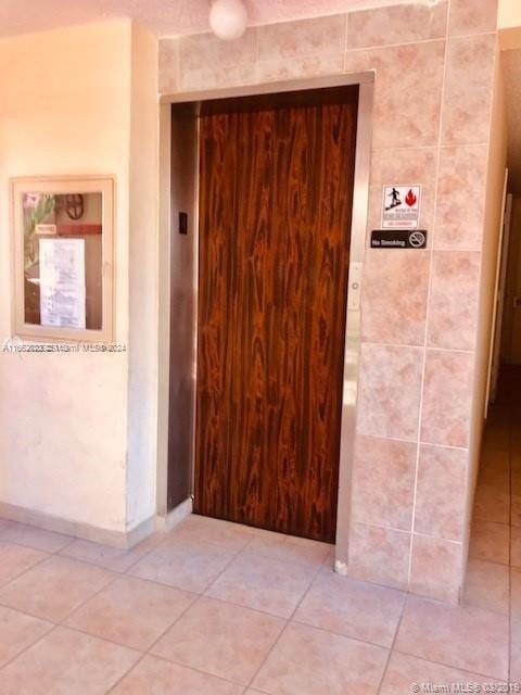 corridor with elevator and tile patterned floors