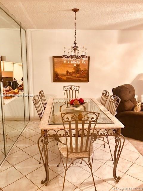 dining room featuring a textured ceiling, a chandelier, and tile patterned floors