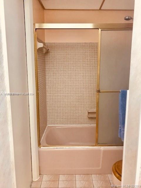 bathroom featuring shower / bath combination with glass door, toilet, and tile patterned floors