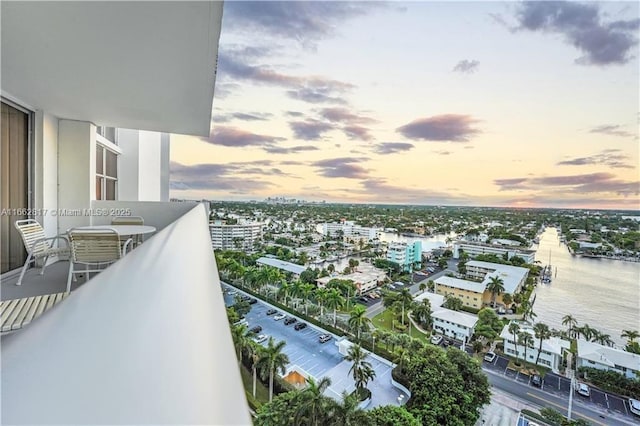 balcony at dusk featuring a water view