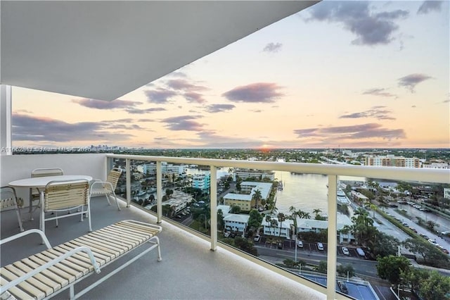 balcony at dusk featuring a water view