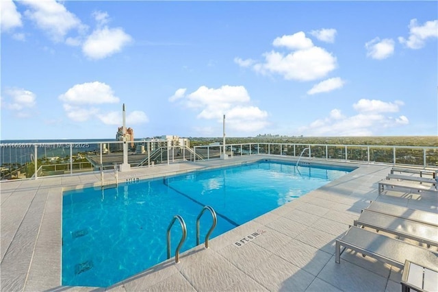 view of swimming pool with a water view and a patio area