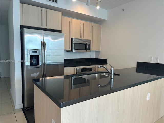 kitchen with light brown cabinets, sink, light tile patterned floors, kitchen peninsula, and stainless steel appliances