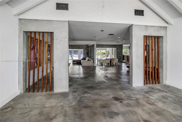 entrance foyer with vaulted ceiling with beams and concrete floors