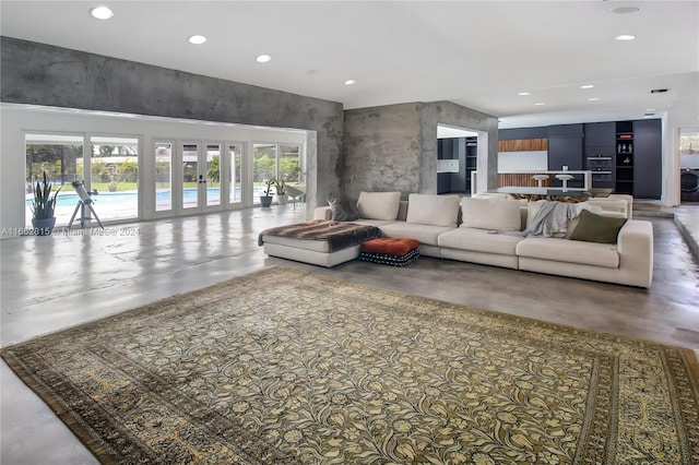 living room featuring french doors, a wealth of natural light, and concrete flooring