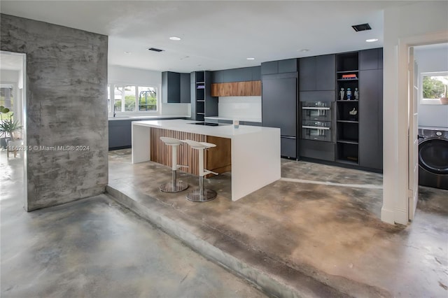 kitchen with a wealth of natural light, stainless steel built in fridge, a kitchen bar, and a center island