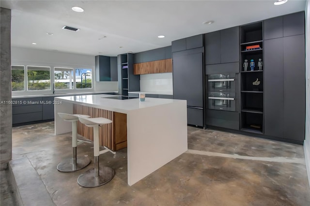 kitchen with black appliances, a kitchen bar, concrete flooring, and a center island