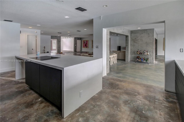 kitchen featuring a large island, a textured ceiling, and black electric stovetop