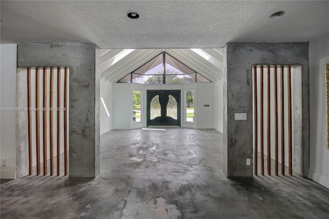 entrance foyer with vaulted ceiling, a textured ceiling, and concrete flooring