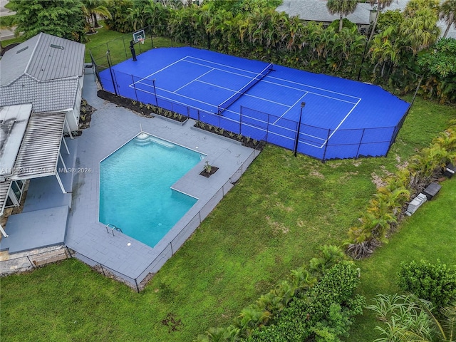 view of swimming pool featuring tennis court and a yard