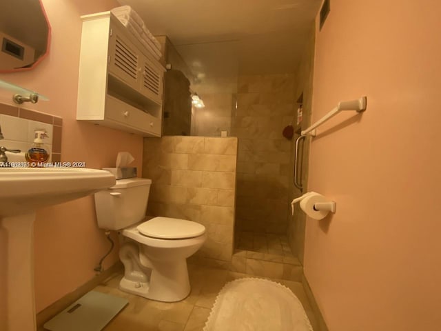 bathroom featuring a tile shower, toilet, and tile patterned floors