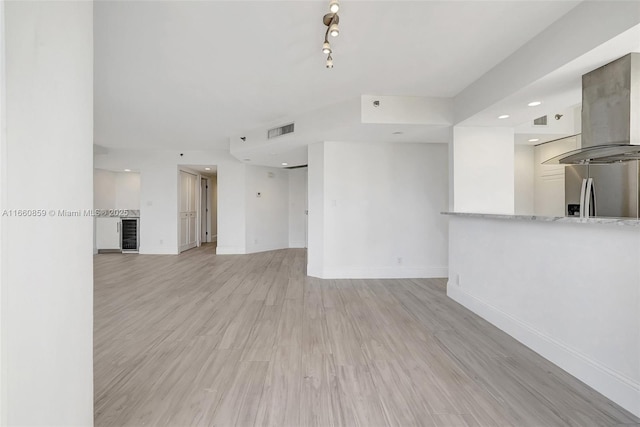unfurnished living room featuring light wood-style flooring, baseboards, and visible vents