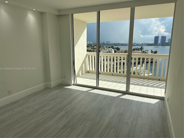 unfurnished room featuring light wood-type flooring and a water view