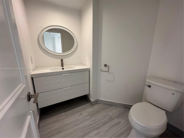 bathroom featuring wood-type flooring, vanity, and toilet