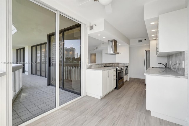 kitchen with visible vents, ventilation hood, stainless steel electric range, white cabinetry, and a sink