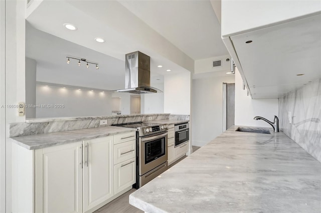 kitchen featuring visible vents, island exhaust hood, a sink, white cabinetry, and appliances with stainless steel finishes