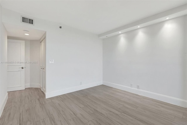 empty room with recessed lighting, baseboards, visible vents, and light wood finished floors