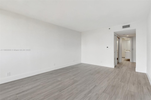 empty room with visible vents, baseboards, and light wood-style floors