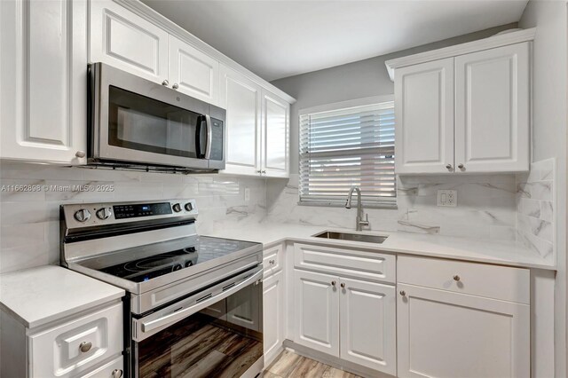 kitchen with sink, decorative backsplash, white cabinets, and appliances with stainless steel finishes