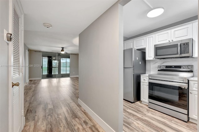 kitchen with appliances with stainless steel finishes, backsplash, white cabinets, and light hardwood / wood-style floors