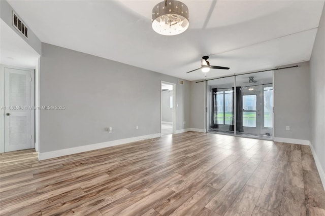 spare room featuring ceiling fan with notable chandelier and light hardwood / wood-style floors