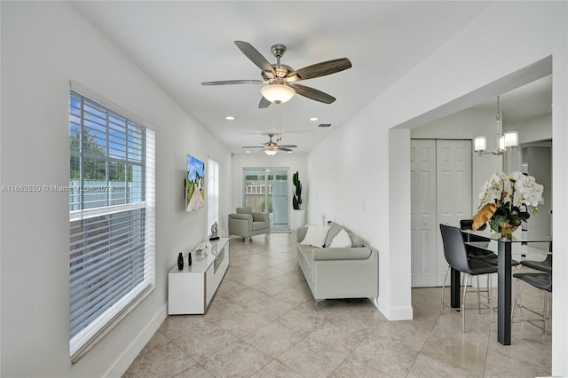 living room with ceiling fan with notable chandelier