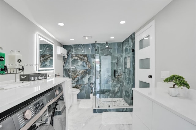 bathroom featuring vanity, a shower with shower door, toilet, and washing machine and clothes dryer