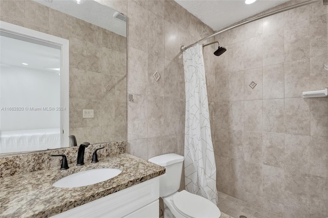 bathroom featuring tile walls, toilet, vanity, and curtained shower