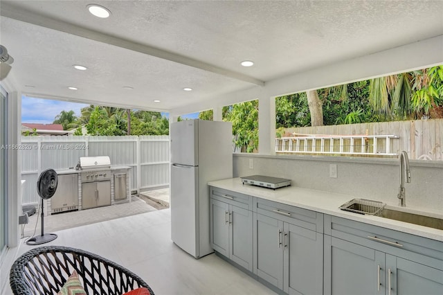 kitchen with a textured ceiling, a healthy amount of sunlight, and white fridge