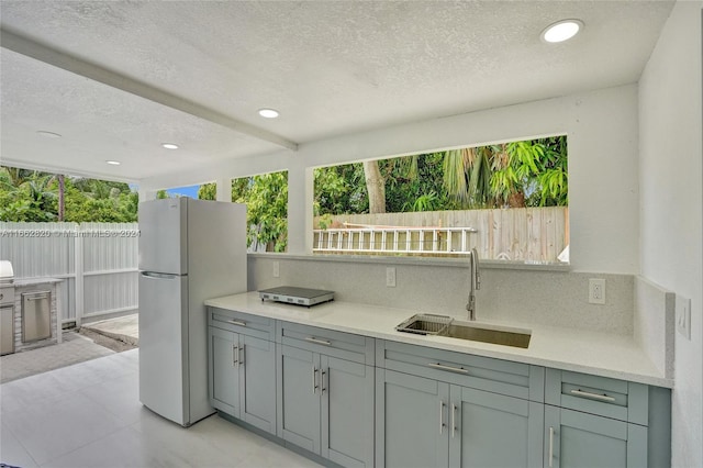 kitchen featuring sink, white fridge, and a textured ceiling