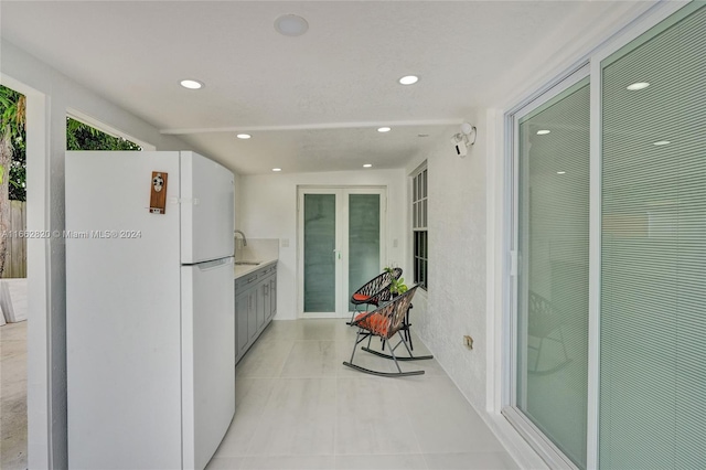 kitchen featuring sink, light tile patterned floors, and white fridge