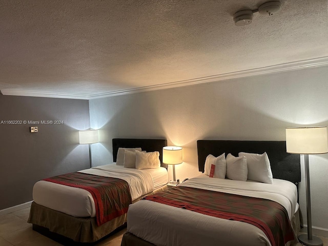 bedroom with ornamental molding, tile patterned flooring, and a textured ceiling