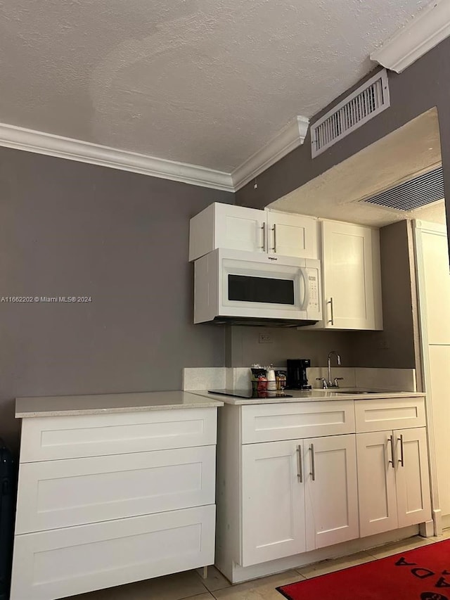 kitchen with white cabinets, a textured ceiling, and ornamental molding