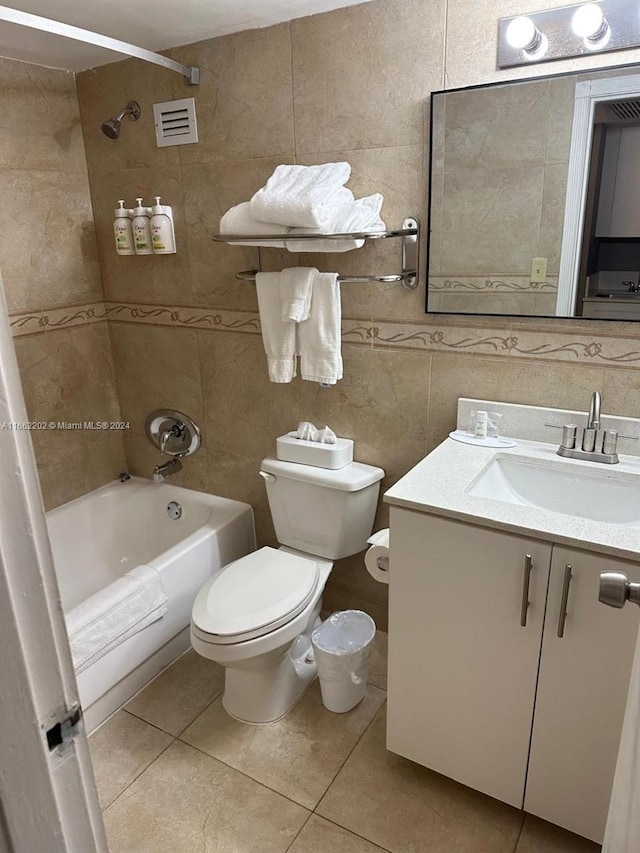 full bathroom featuring tile walls, tile patterned flooring, tiled shower / bath combo, vanity, and toilet