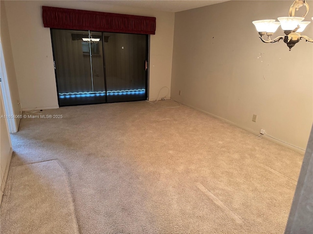 carpeted empty room with a notable chandelier