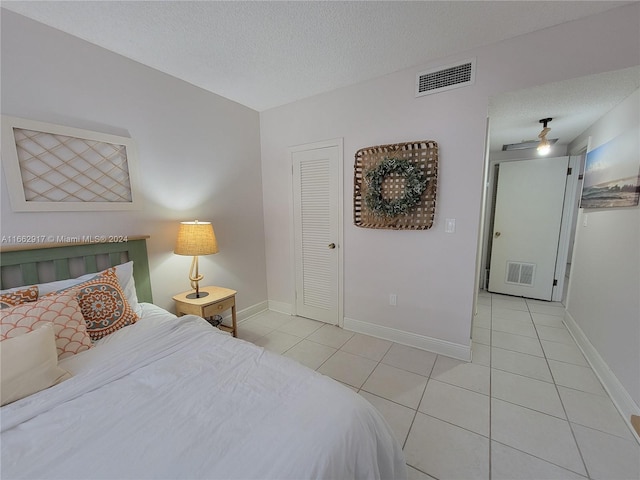 tiled bedroom with a closet and a textured ceiling