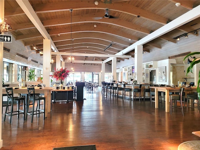 interior space with high vaulted ceiling, rail lighting, beamed ceiling, and dark hardwood / wood-style flooring