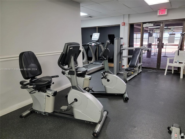 gym with french doors and a paneled ceiling