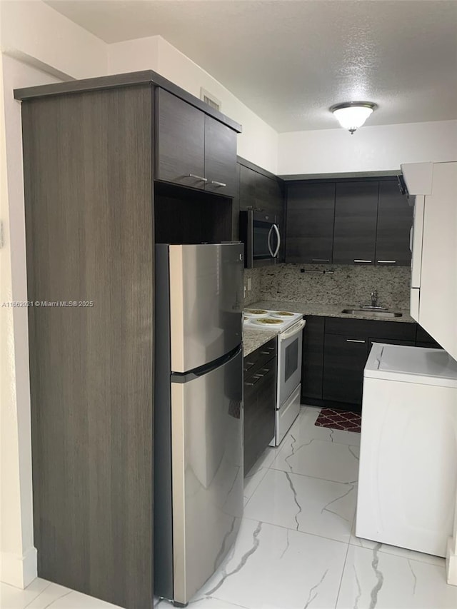 kitchen with washer / clothes dryer, sink, backsplash, stainless steel appliances, and a textured ceiling