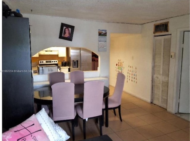 tiled dining space featuring a textured ceiling