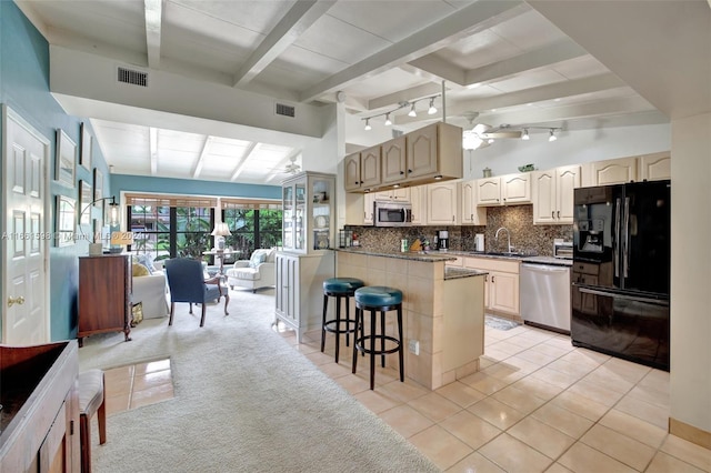 kitchen featuring light tile patterned floors, stainless steel appliances, a kitchen bar, beam ceiling, and ceiling fan