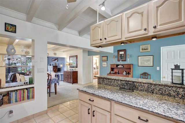 kitchen with rail lighting, light stone counters, beamed ceiling, ceiling fan, and light colored carpet