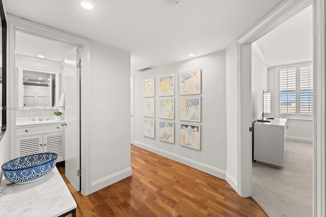 hall with hardwood / wood-style flooring, ornamental molding, and sink