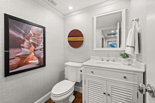 bathroom with toilet, wood-type flooring, ornamental molding, and vanity